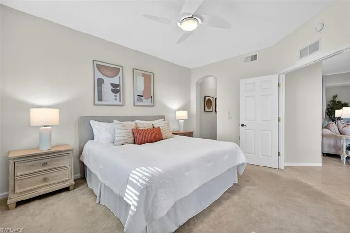 Bedroom featuring ceiling fan, light colored carpet, and arched walkways