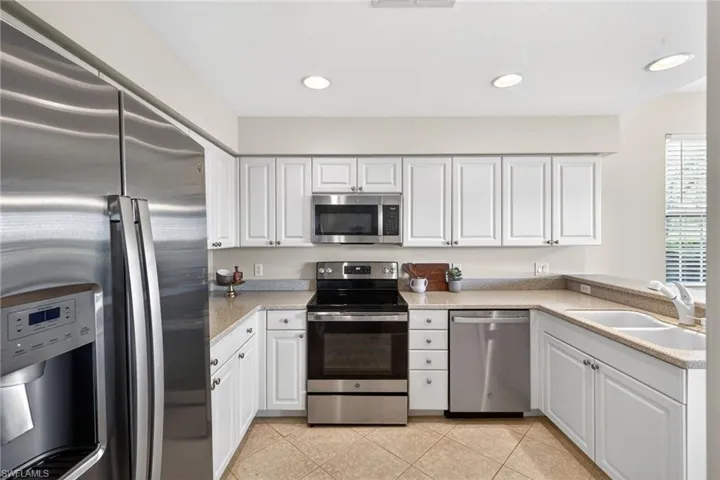 Kitchen featuring stainless steel appliances, white cabinets, recessed lighting, light tile patterned floors, and a peninsula