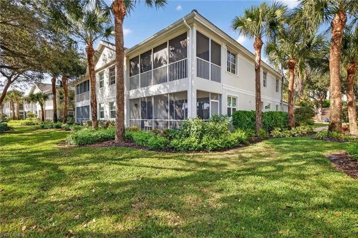 Rear view of property featuring a sunroom, a lawn, and a balcony