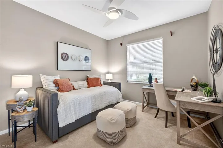 Bedroom featuring light colored carpet, an office area, and a ceiling fan