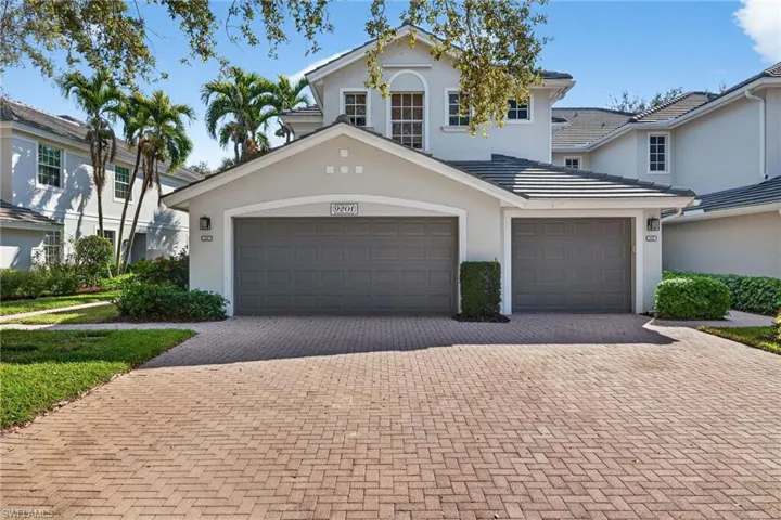 Traditional home featuring decorative driveway and stucco siding