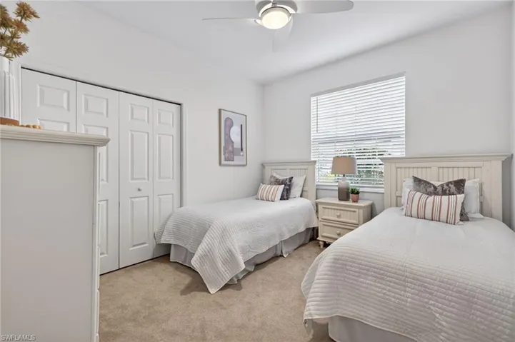 Bedroom with light colored carpet, a closet, and a ceiling fan