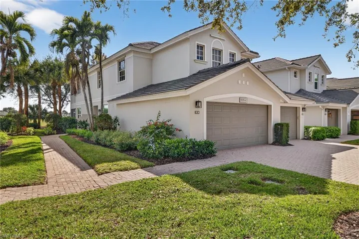 Traditional-style home with a front yard, stucco siding, and decorative driveway