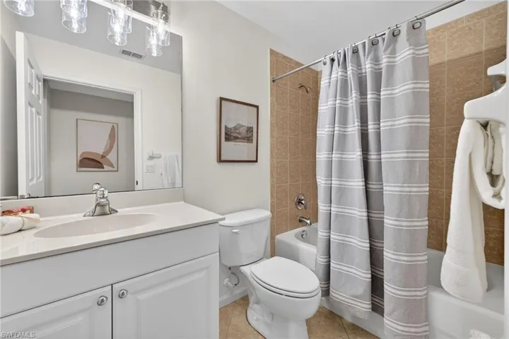 Full bathroom with vanity, shower / bathtub combination with curtain, and light tile patterned flooring