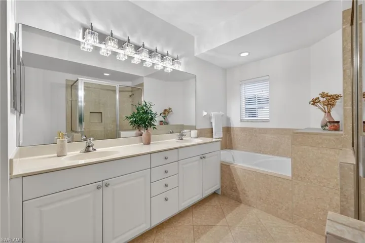 Bathroom with a stall shower, double vanity, a garden tub, and light tile patterned floors