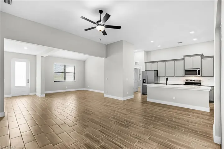 Unfurnished living room with ceiling fan, wood tiled floors, and recessed lighting