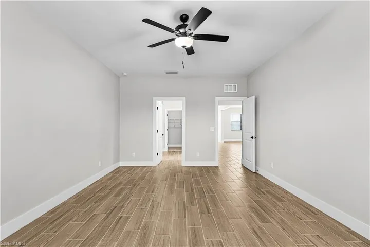 Unfurnished bedroom featuring a spacious closet, wood tiled floors, and ceiling fan