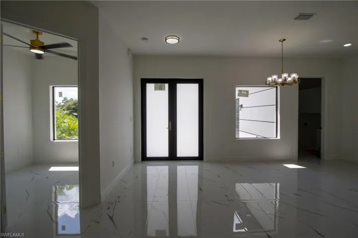 Tiled empty room with ceiling fan with notable chandelier