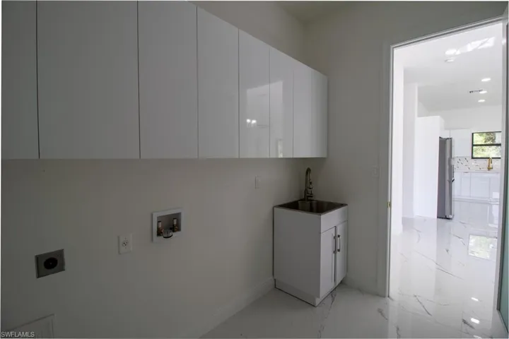Laundry area featuring sink, cabinets, hookup for an electric dryer, hookup for a washing machine, and light tile patterned floors