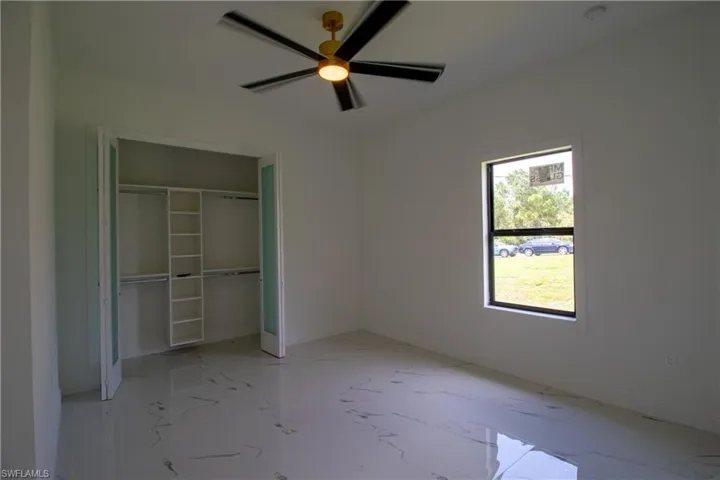 Unfurnished bedroom with ceiling fan, light tile patterned floors, and a closet