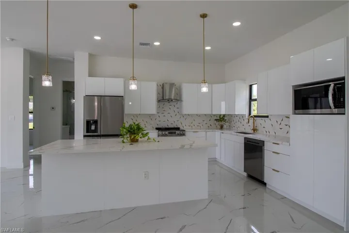 Kitchen with wall chimney range hood, tasteful backsplash, appliances with stainless steel finishes, and light tile patterned flooring