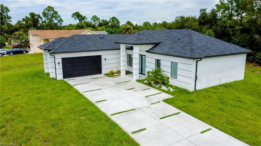 Ranch-style home featuring a garage and a front lawn