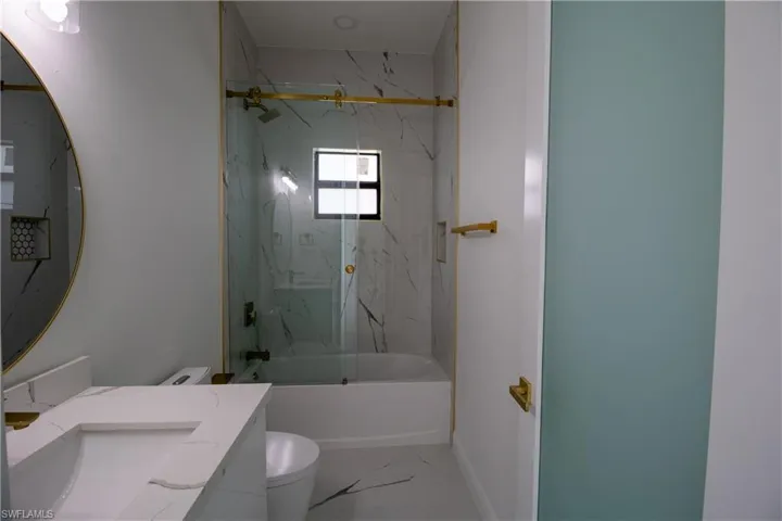 Full bathroom with tile patterned flooring, toilet, tiled shower / bath combo, and sink