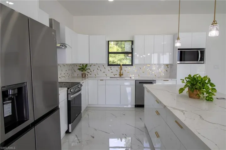 Kitchen featuring backsplash, stainless steel appliances, wall chimney exhaust hood, sink, and light stone countertops