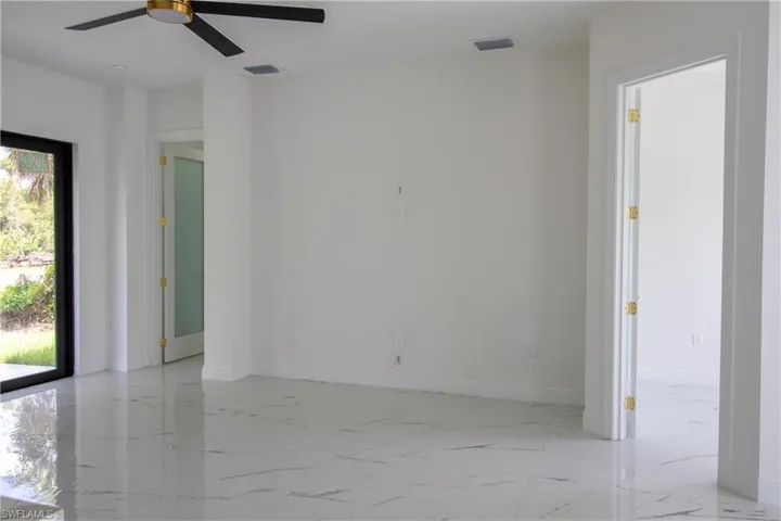 Empty room with light tile patterned floors, plenty of natural light, and ceiling fan