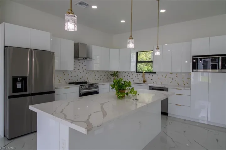 Kitchen featuring stainless steel appliances, a kitchen island, decorative backsplash, and wall chimney range hood
