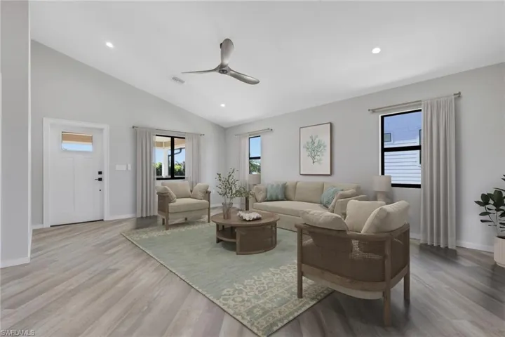 Living area with a ceiling fan, vaulted ceiling, light wood-style flooring, and recessed lighting