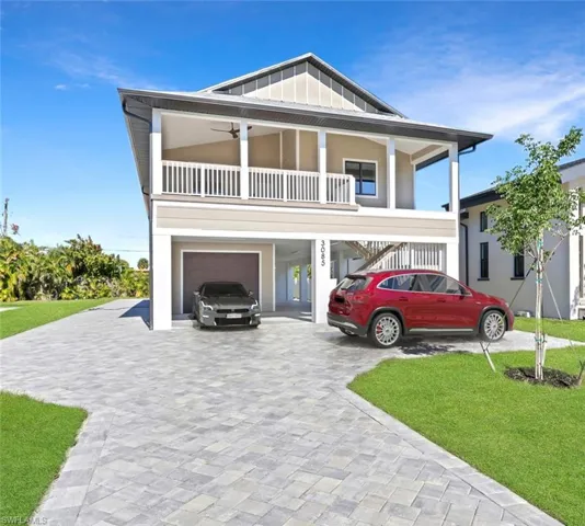 Beach home featuring decorative driveway, a front yard, a carport, stairway, and board and batten siding
