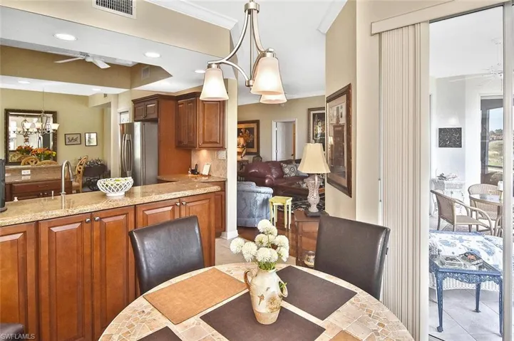 Tiled dining area with recessed lighting, ornamental molding, visible vents, and ceiling fan with notable chandelier