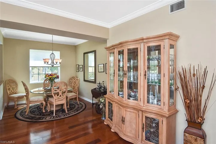 Dining room with visible vents, crown molding, baseboards, a chandelier, and dark wood-style flooring