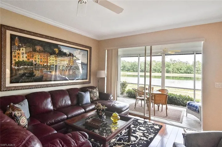 Living room with a ceiling fan, a water view, and ornamental molding
