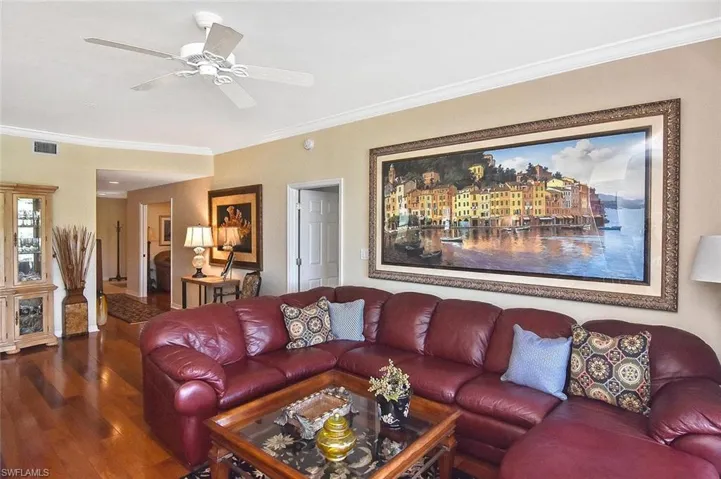 Living area featuring a ceiling fan, crown molding, wood finished floors, and visible vents