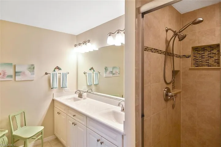 Bathroom featuring a sink, double vanity, and tiled shower