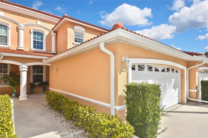 View of side of property featuring stucco siding, driveway, a tiled roof, and a garage