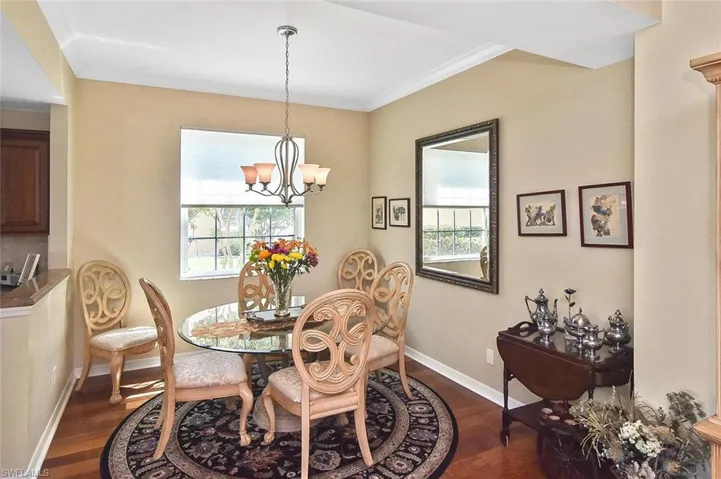 Dining room with dark wood finished floors, a wealth of natural light, and a notable chandelier