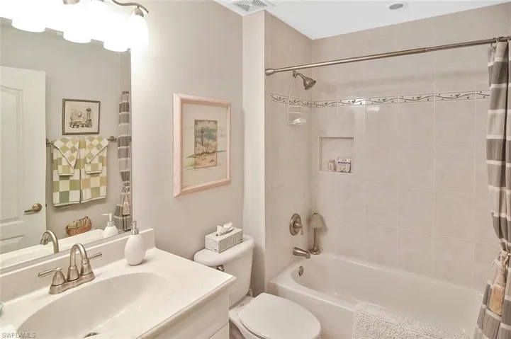 Full bathroom featuring shower / bath combo with shower curtain, visible vents, vanity, and toilet