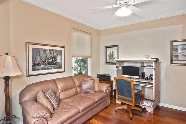 Living room featuring wood finished floors, crown molding, baseboards, and a ceiling fan