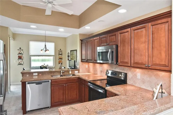 Kitchen with recessed lighting, a sink, decorative backsplash, a peninsula, and appliances with stainless steel finishes