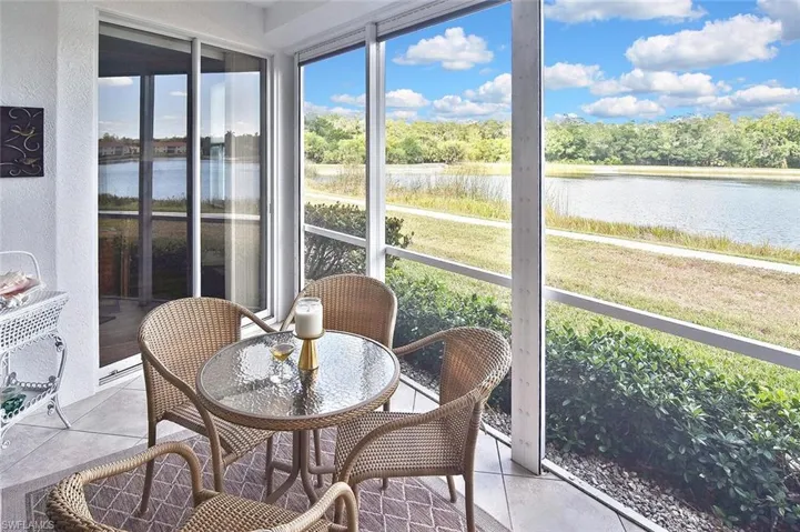 Sunroom featuring a textured wall, a water view, and tile patterned floors