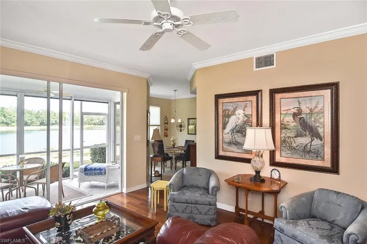 Living room with baseboards, visible vents, ornamental molding, and ceiling fan