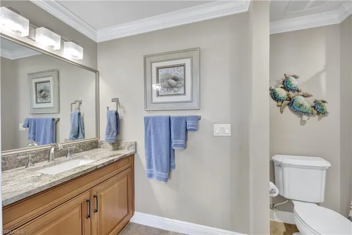 Bathroom with toilet, ornamental molding, vanity, and tile patterned floors