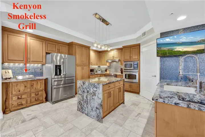 Kitchen featuring decorative backsplash, a kitchen island, hanging light fixtures, stainless steel appliances, and sink