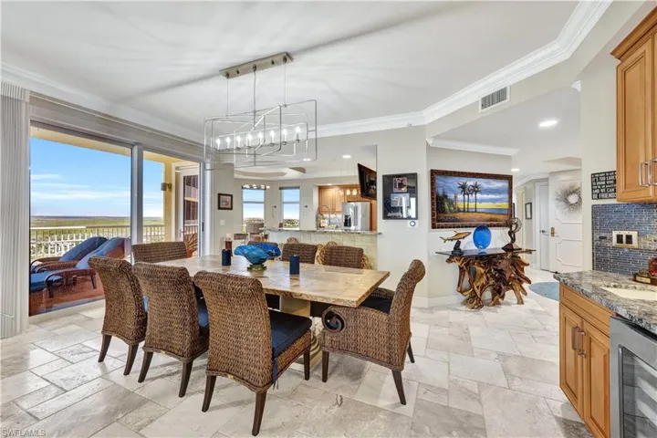 Dining room with wine cooler, ornamental molding, sink, and a notable chandelier