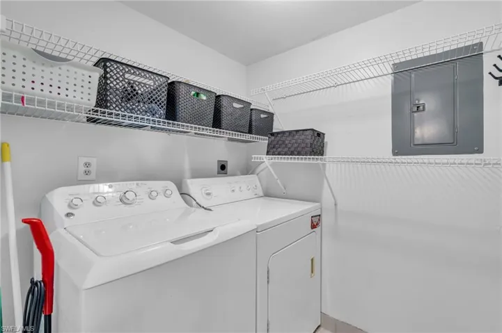Laundry area and pantry off kitchen featuring washer and dryer, storage and electric panel