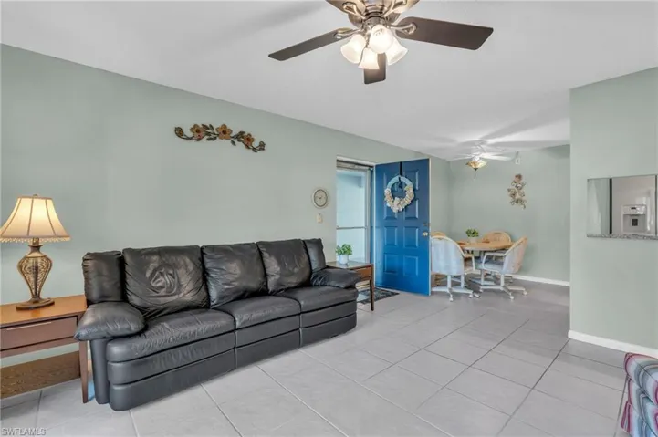 Tiled living room featuring ceiling fan and open to dining and kitchen