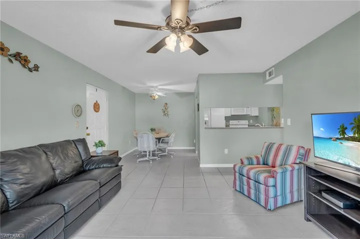 Tiled living room featuring ceiling fan and open to dining and kitchen