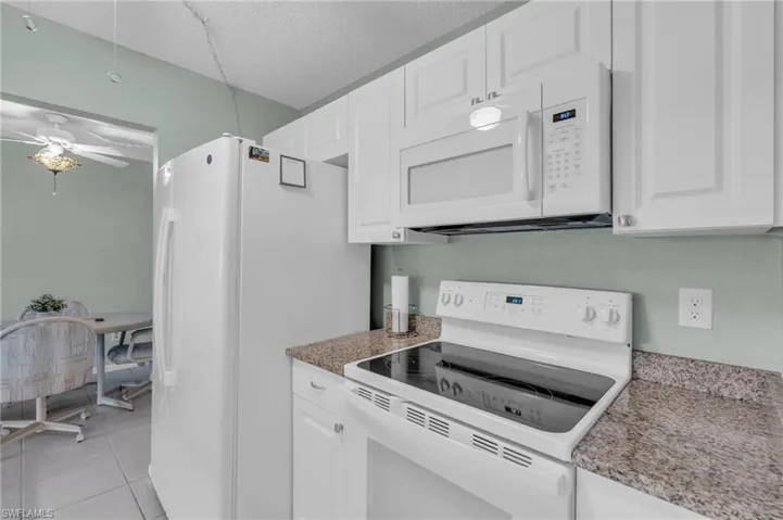 Kitchen white cabinets, granite counter and white appliances