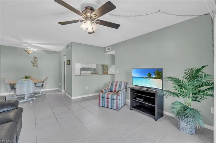 Tiled living room featuring ceiling fan and open to dining and kitchen