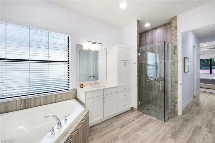 Primary bathroom with glass enclosed shower, dual sinks and tub.
