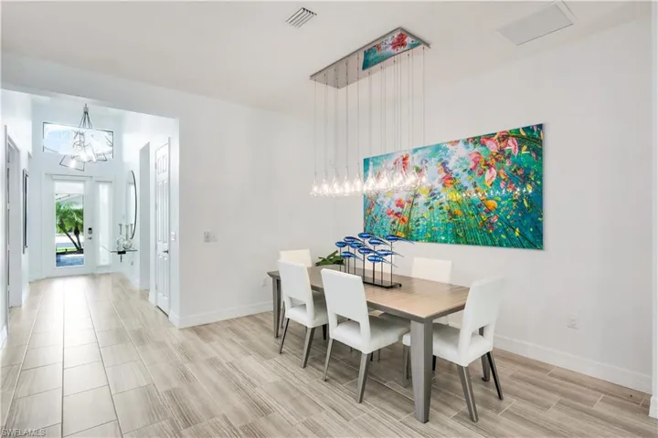 Dining area with custom lighting and hallway to front door access.