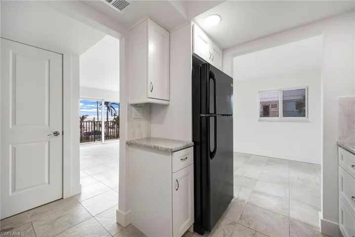 Kitchen featuring black fridge and white cabinets
