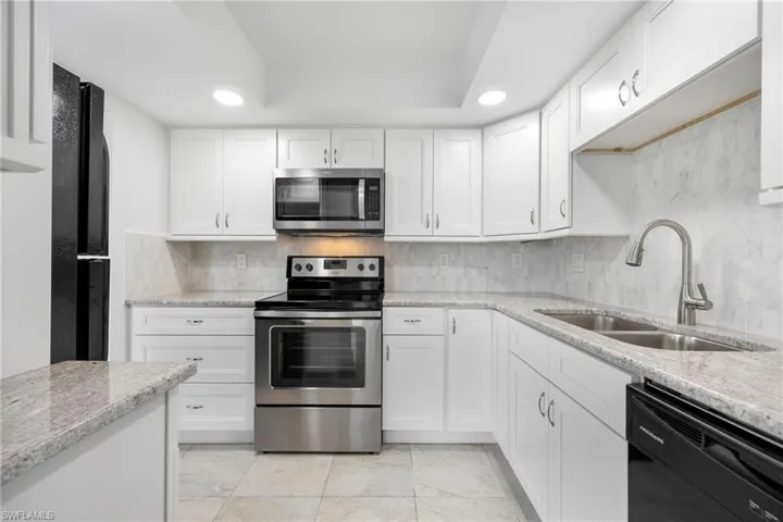 Kitchen featuring white cabinetry, sink, decorative backsplash, and appliances with stainless steel finishes