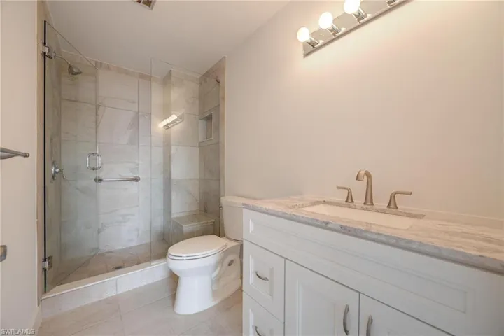 Bathroom with walk in shower, vanity, tile patterned floors, and toilet