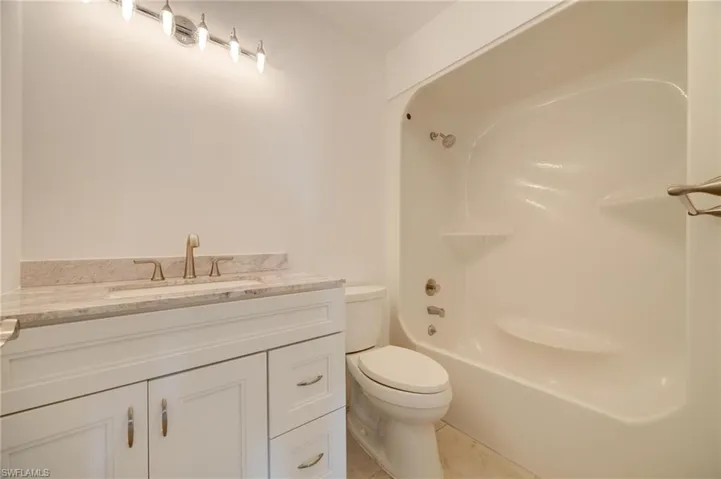 Full bathroom with vanity, tub / shower combination, tile patterned floors, and toilet