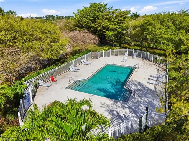 Community pool with a patio area and view of wooded area