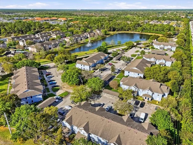 Aerial perspective of suburban area featuring a nearby body of water and a tree filled landscape